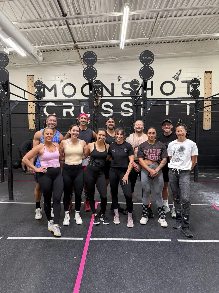Moonshot CrossFit members posing together in front of the Moonshot CrossFit wall