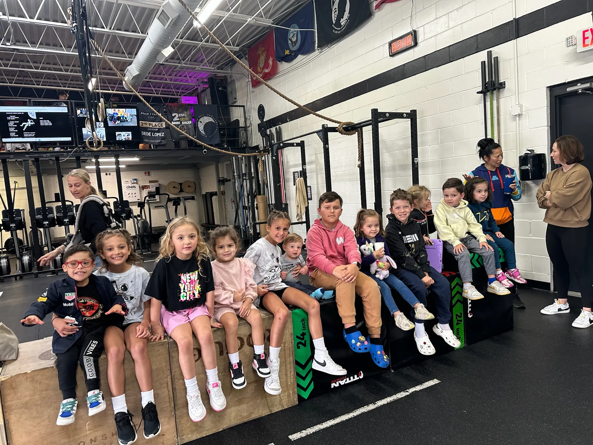 Kids from the Moonshot CrossFit youth program sitting together on boxes at the gym