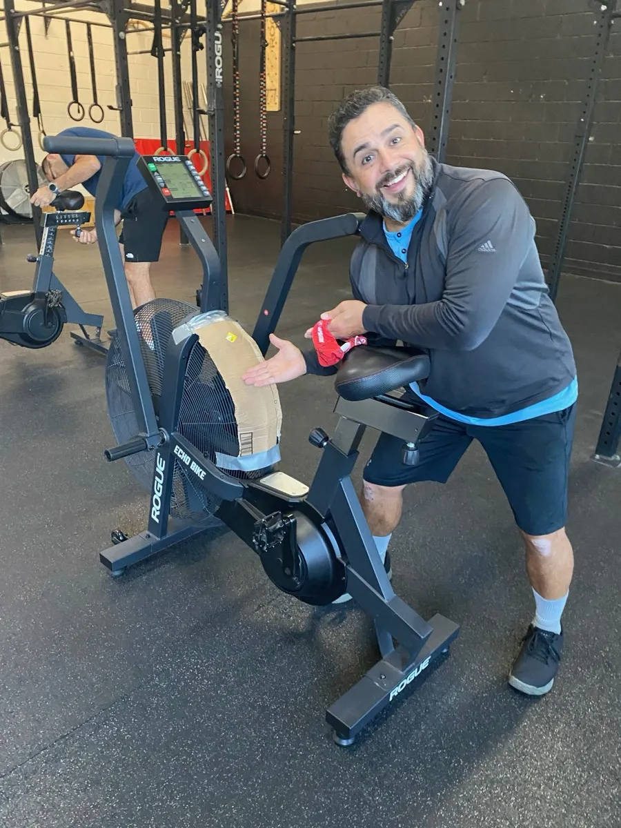 A Moonshot CrossFit member smiling on the assault bike during a workout