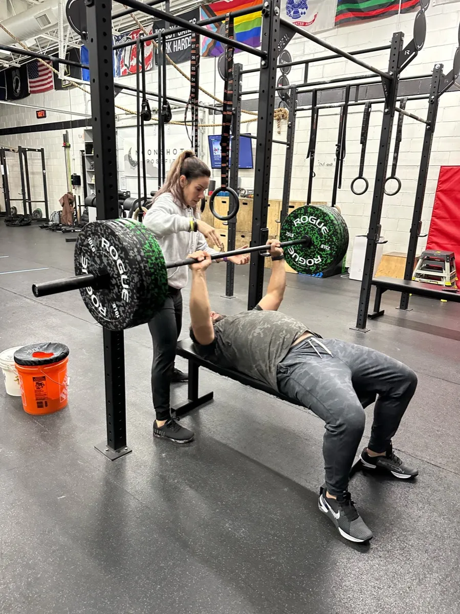 A member spotting another during a bench press at Moonshot CrossFit