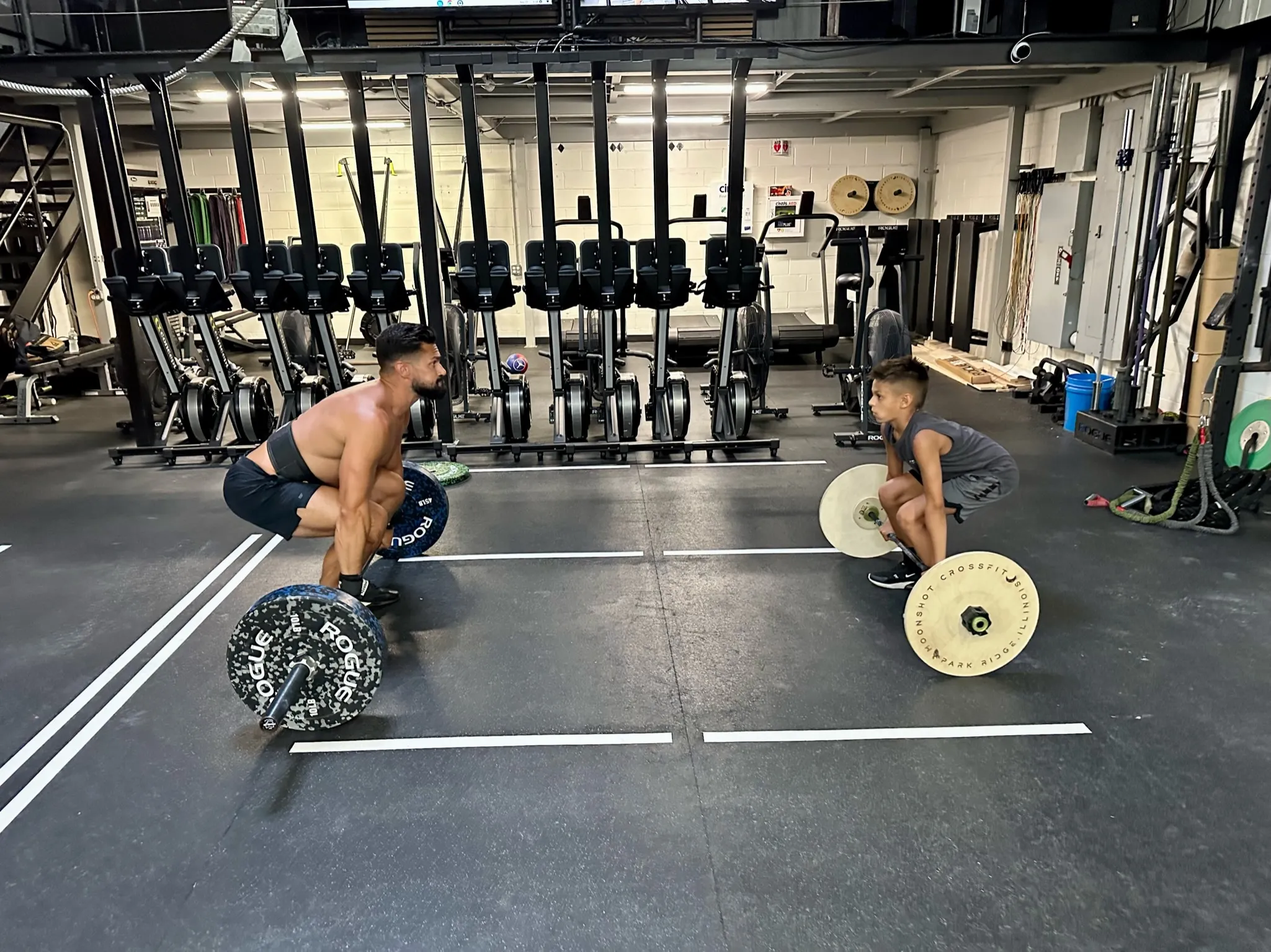 Coach teaching a young athlete proper lifting form